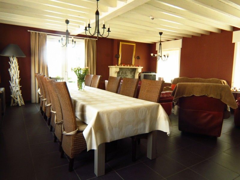 Aussenansicht des Ferienhauses Hof ter Harte, Ypern, Westflandern, mit roten Akzenten und bluehenden Hortensien.