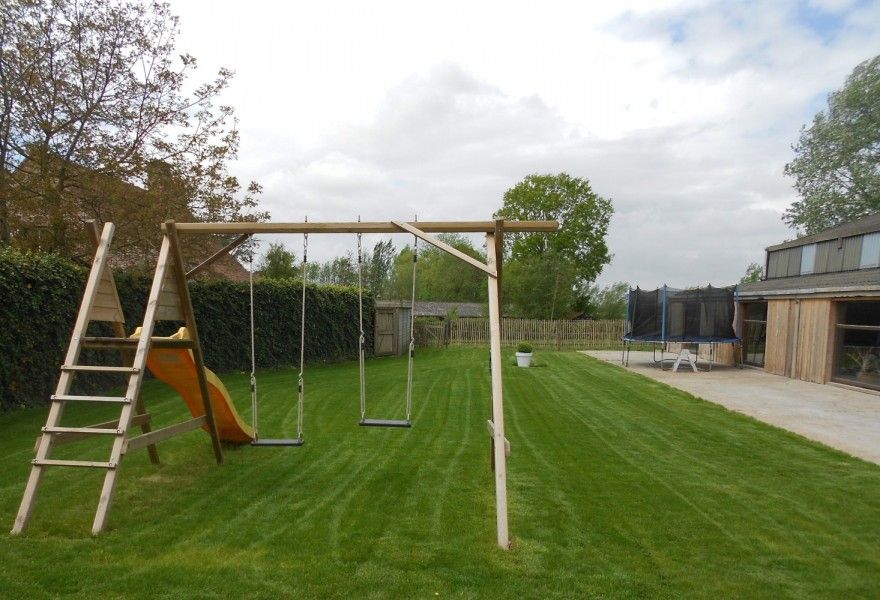 Geraeumige Scheune im Ferienhaus Hof ter Harte, Ypern, Westflandern, mit Holzstapeln und bluehenden Pflanzen.