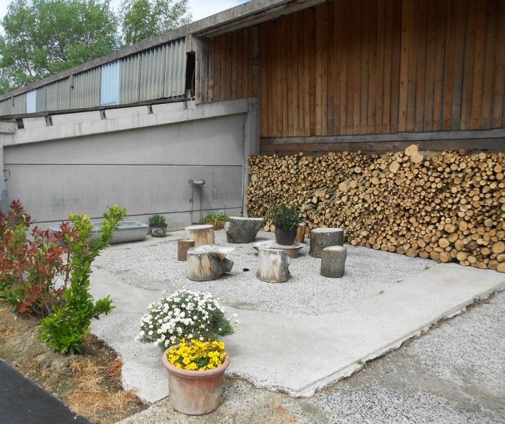Aussensitzplatz im Ferienhaus Hof ter Harte, Ypern, Westflandern, mit Holzbaenken und Blumen.