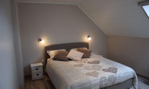 Gezellige woonkamer in Reutelhoeve vakantiehuis in Zonnebeke, West-Vlaanderen met open haard en comfortabele stoelen.