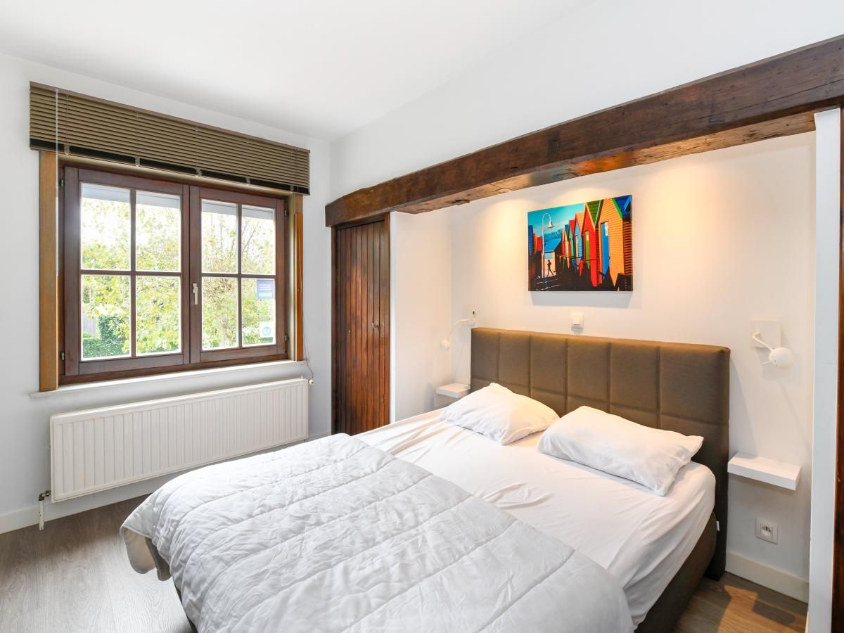 Gezellige slaapkamer in vakantiehuis Floribert, Nieuwpoort-Bad, met comfortabel tweepersoonsbed en rustgevend uitzicht op de tuin.