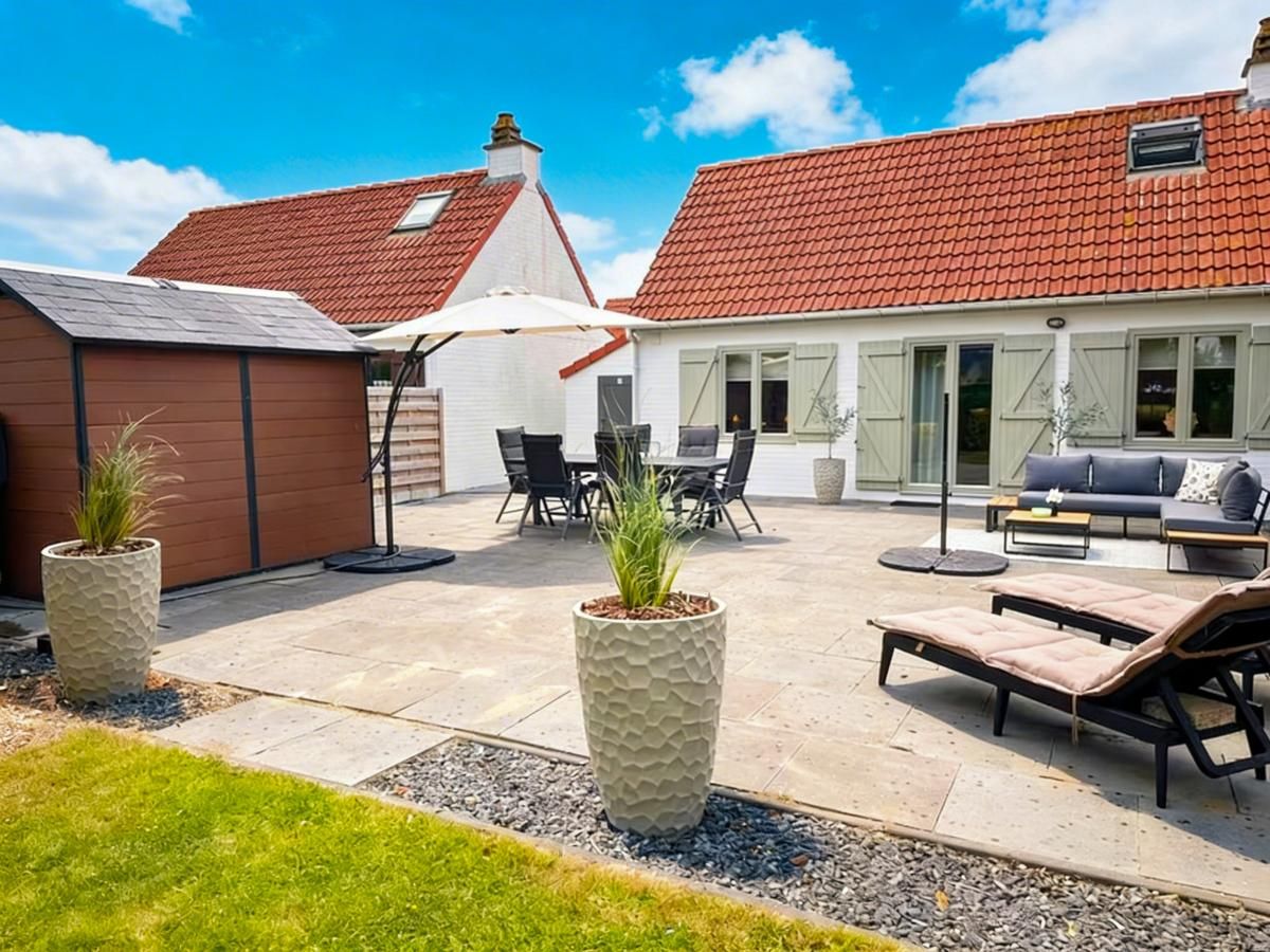 Geraeumige Terrasse der Villa Belle Haan in De Haan, Belgien, mit bequemen Sitzgelegenheiten und Sonnenschirmen fuer ein entspannendes Ferienerlebnis.