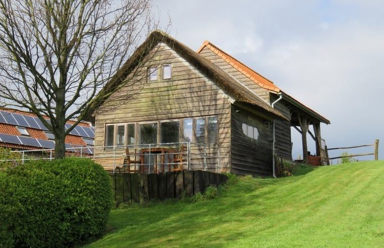 Gemuetliches Ferienhaus in Dranouter, Westflandern, mit Holzfassade und sonniger Terrasse, umgeben von gruener Natur.