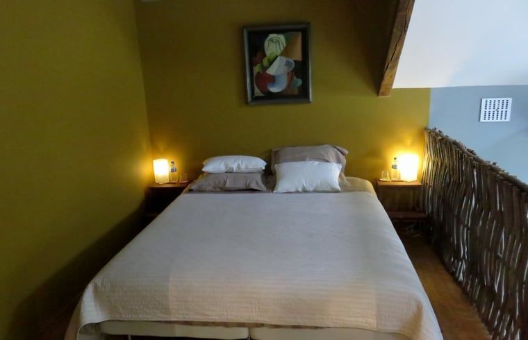 Gemuetliches Schlafzimmer im Ferienhaus in Dranouter, Westflandern, Belgien, mit stimmungsvoller Beleuchtung und Kunst an der Wand.