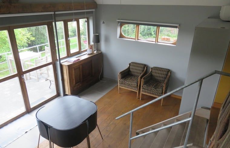 Gemuetliches Wohnzimmer im Ferienhaus in Dranouter, Westflandern, mit Blick auf die gruene Umgebung und gemuetlicher Sitzecke.