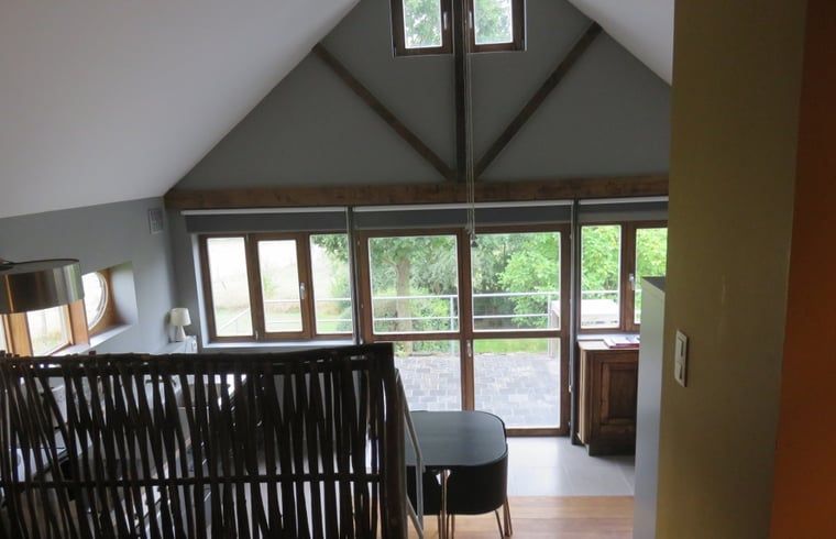 Helle Einrichtung des Ferienhauses in Dranouter, Westflandern, mit Blick auf die gruene Umgebung vom Wohnzimmer aus.