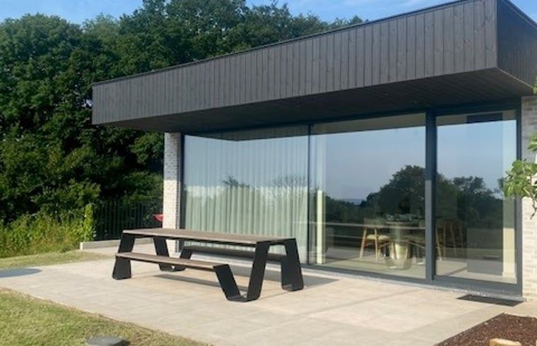 Geraeumige Veranda des Ferienhauses in Heuvelland, Westouter, mit Glaswaenden und Blick auf die Natur in Westflandern, Belgien.