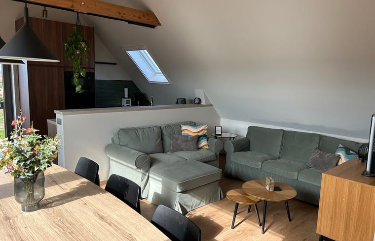 Gemuetliches Wohnzimmer im Ferienhaus in PROVEN, Westflandern, mit komfortabler Sitzecke und moderner Kueche in heimeliger Atmosphaere.
