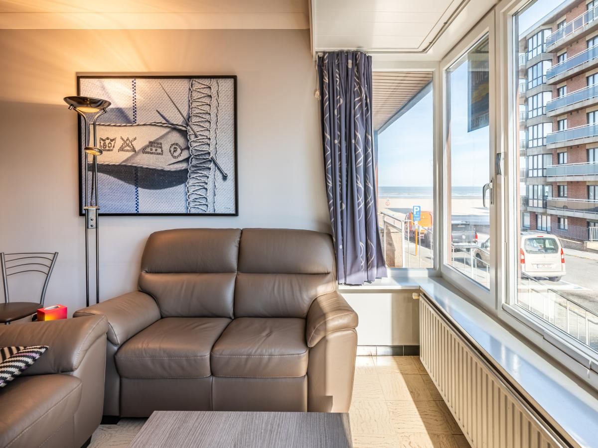 Gezellige woonkamer van Apollo Gelijkvloers vakantiehuis in Koksijde, Belgie, met uitzicht op de straat en de zee.