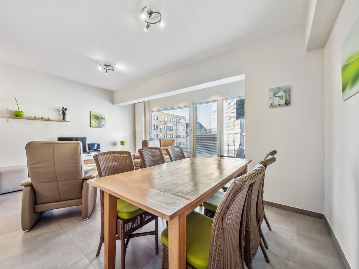 Gezellige eetruimte in vakantiehuis Azcona Twee, Koksijde, met een uitnodigende houten tafel en veel natuurlijk licht.