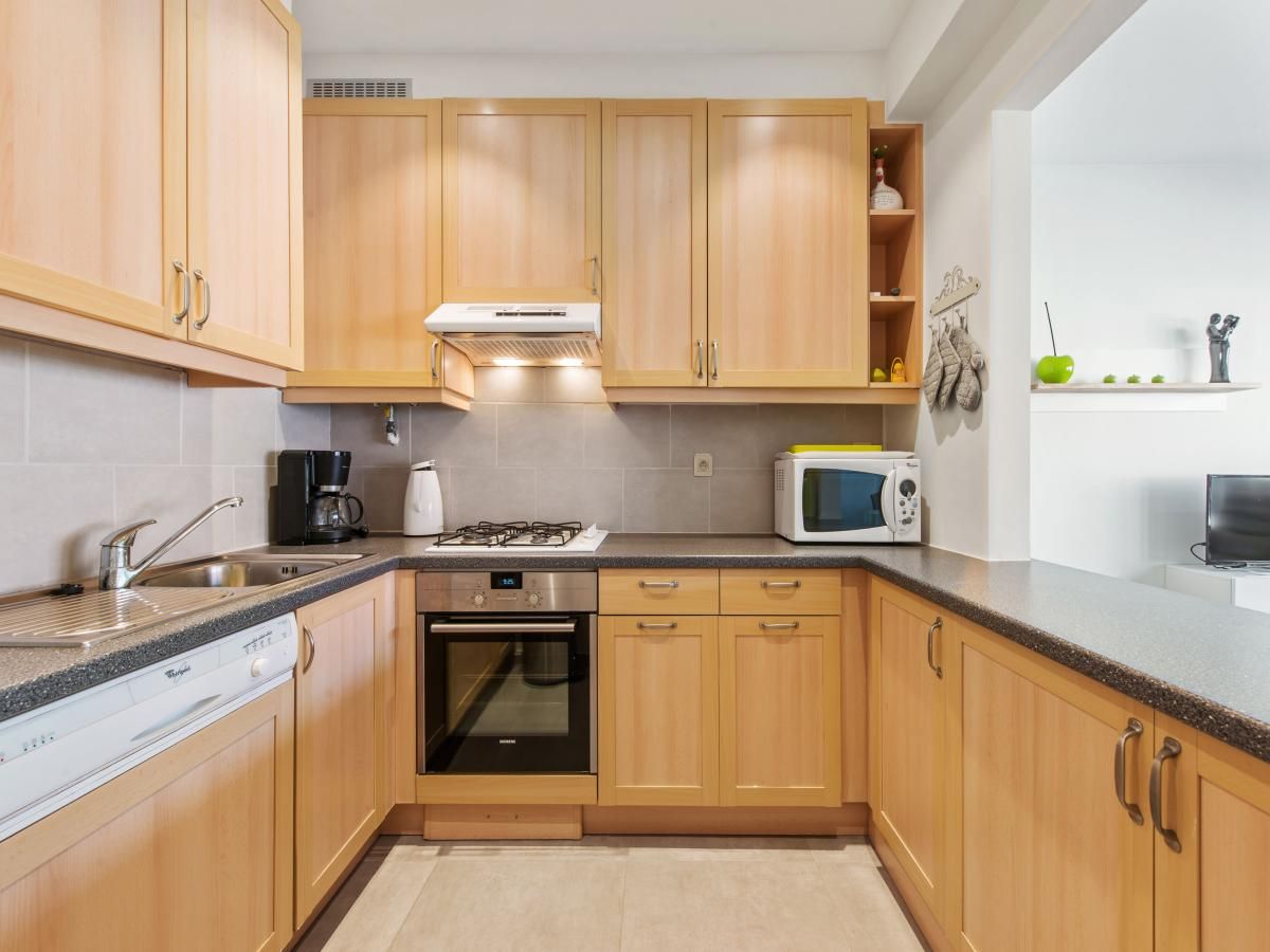 Moderne keuken in vakantiehuis Azcona Twee, Koksijde, West-Vlaanderen, Belgie met houten kasten en moderne apparatuur.