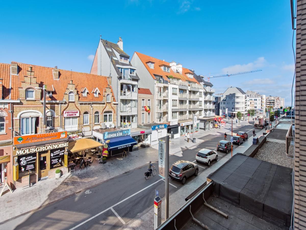 Uitzicht vanaf Azcona Twee vakantiehuis in Koksijde, Belgie, met charmante straat vol winkels en historische architectuur op zonnige dag.