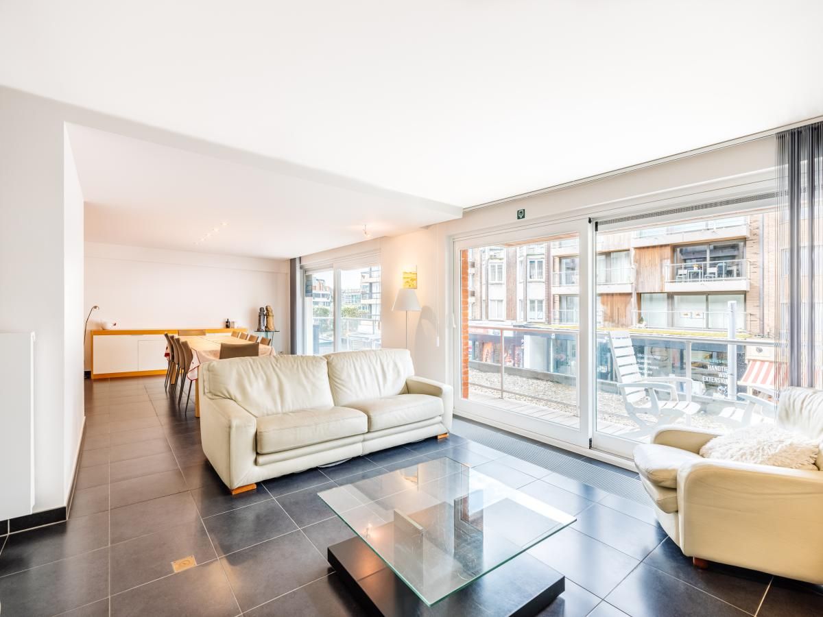 Spacious living room of Brit First vacation home in Koksijde, West Flanders, with modern furnishings and large windows for plenty of natural light.