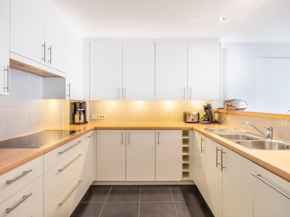 Modern kitchen in Brit First vacation home, Koksijde, West Flanders, with sleek white cabinets and spacious countertops for a comfortable stay.