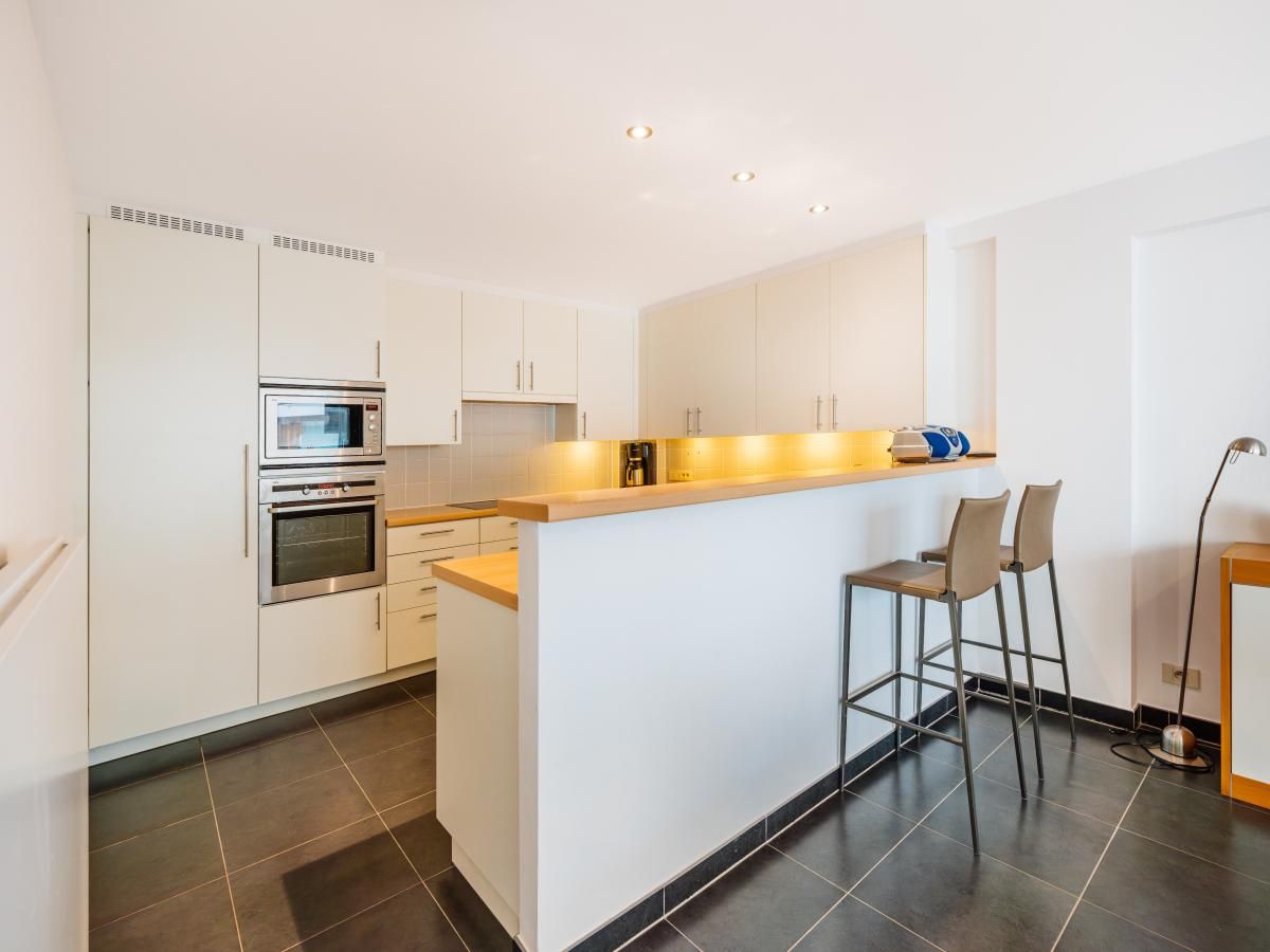 Modern kitchen in vacation home Brit Eerste, Koksijde, West Flanders. Stylish interior with bar and sleek finish.