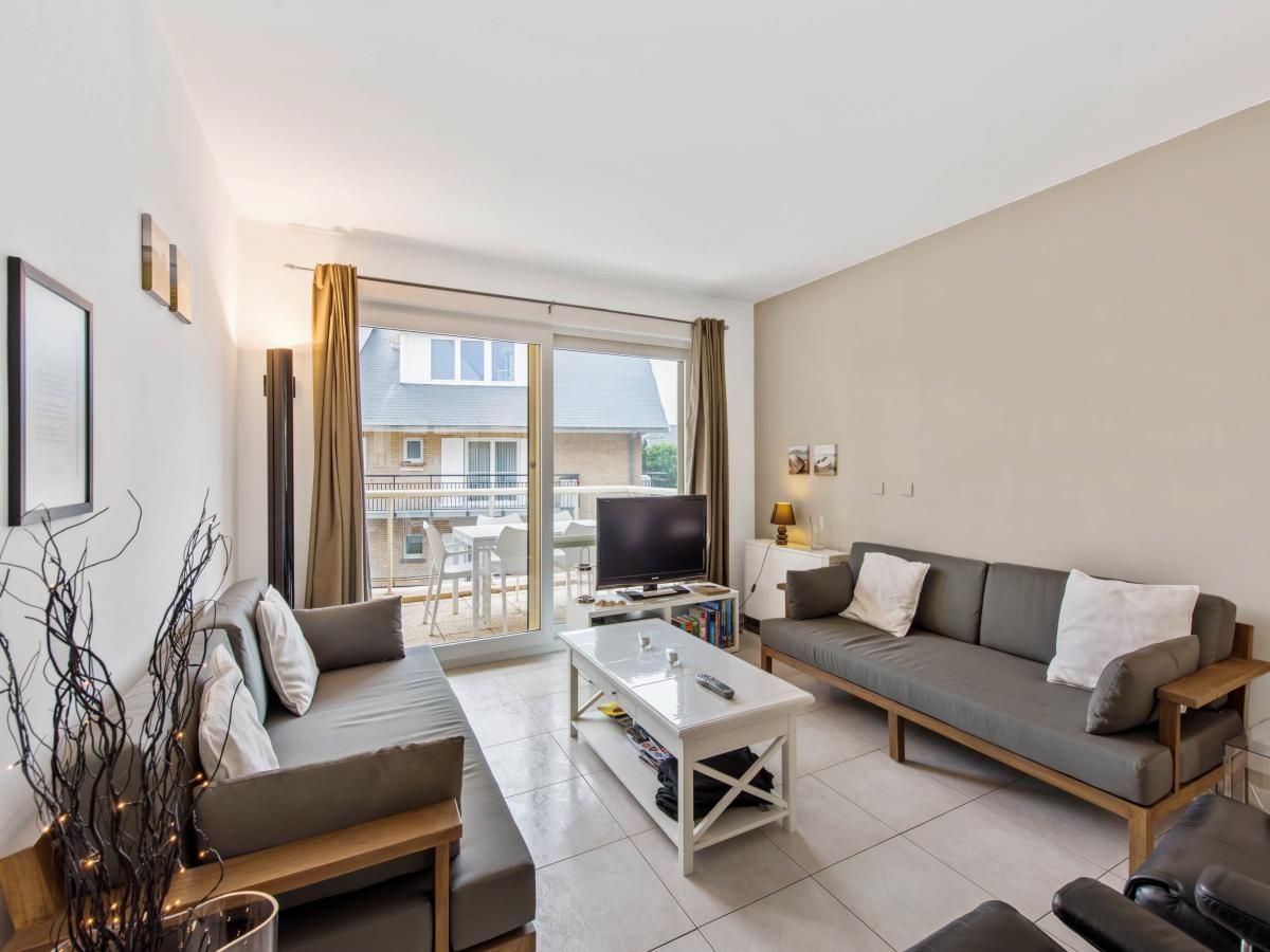 Gezellige woonkamer in Klokjesbloem Gelijkvloers vakantiehuis, Koksijde, Belgie, met uitzicht op het terras en veel natuurlijk licht.