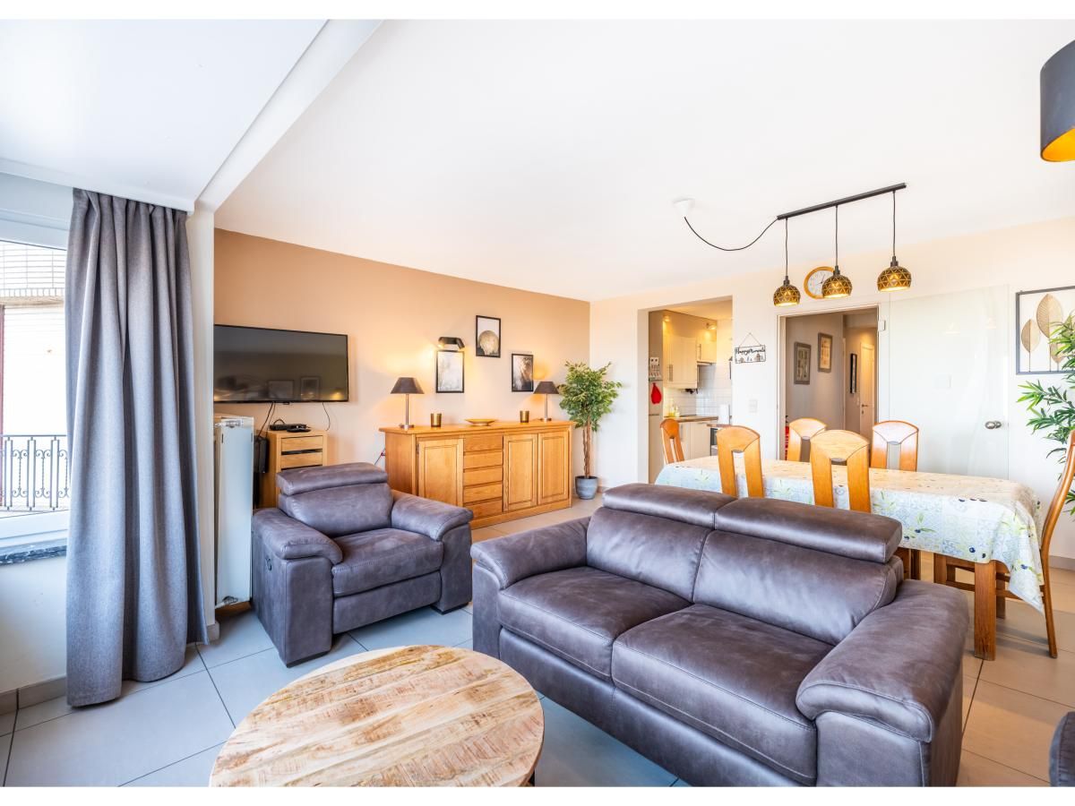 Gezellige woonkamer van vakantiehuis Cortina tweede in Koksijde, West-Vlaanderen met comfortabele zithoek en eethoek voor een ontspannen verblijf.