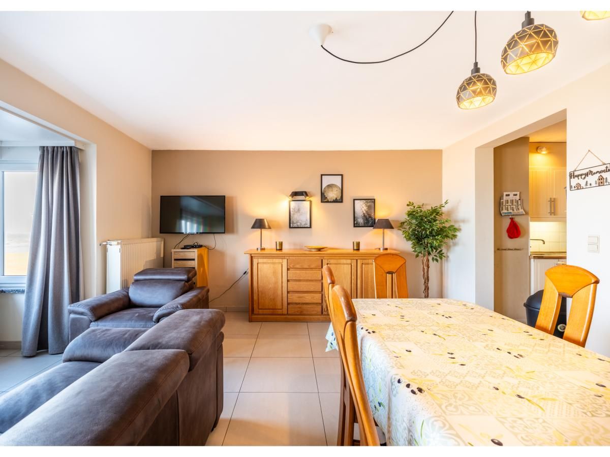 Gezellige woonkamer in vakantiehuis Cortina tweede, Koksijde, West-Vlaanderen met comfortabele zitruimte en eetgedeelte.