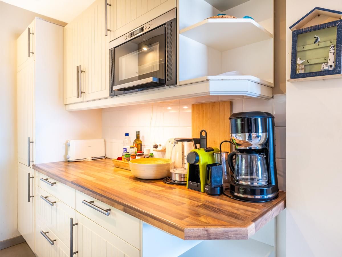 Moderne keuken in Cortina tweede vakantiehuis in Koksijde, West-Vlaanderen met stijlvolle apparatuur en houten werkblad.