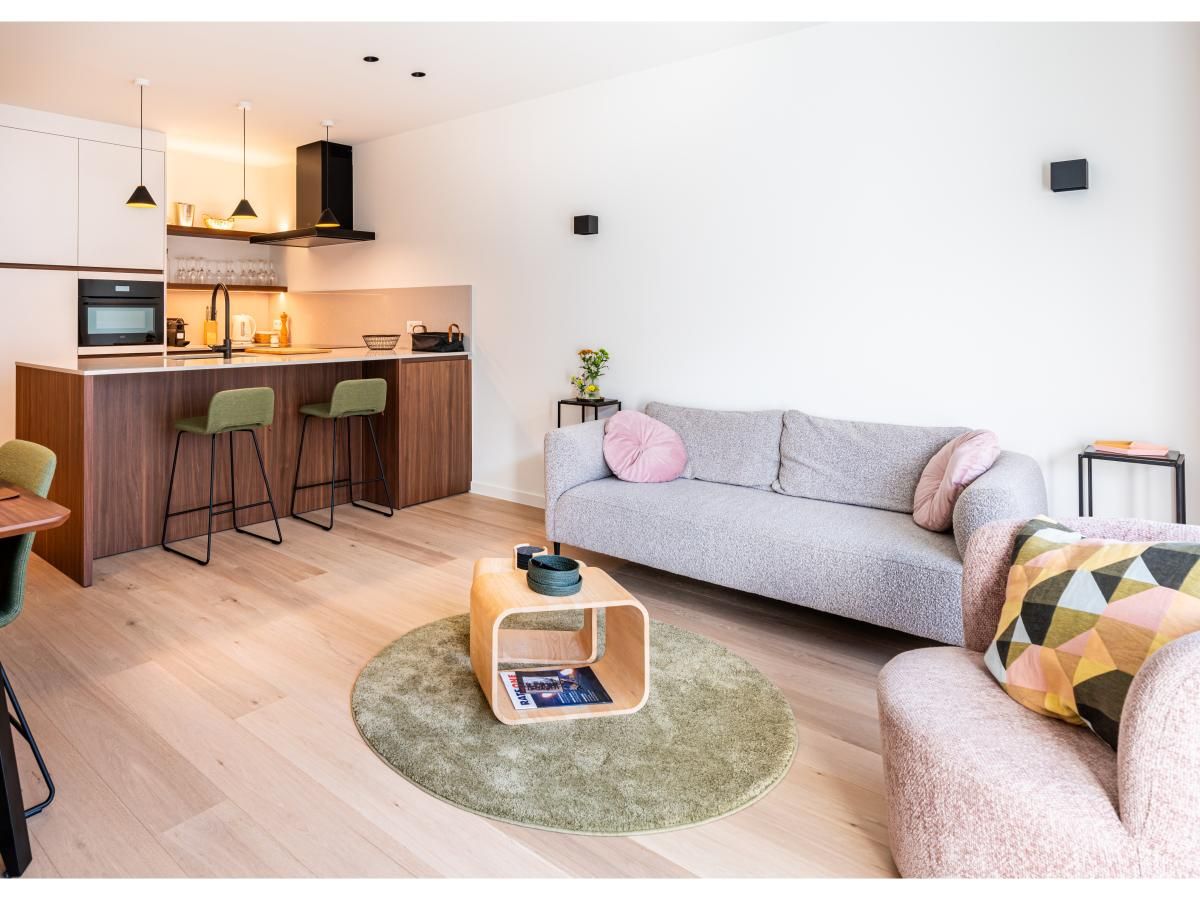 Stijlvolle woonkamer van La Balise Derde vakantiehuis in Koksijde, Belgie, met moderne keuken en comfortabele zithoek.