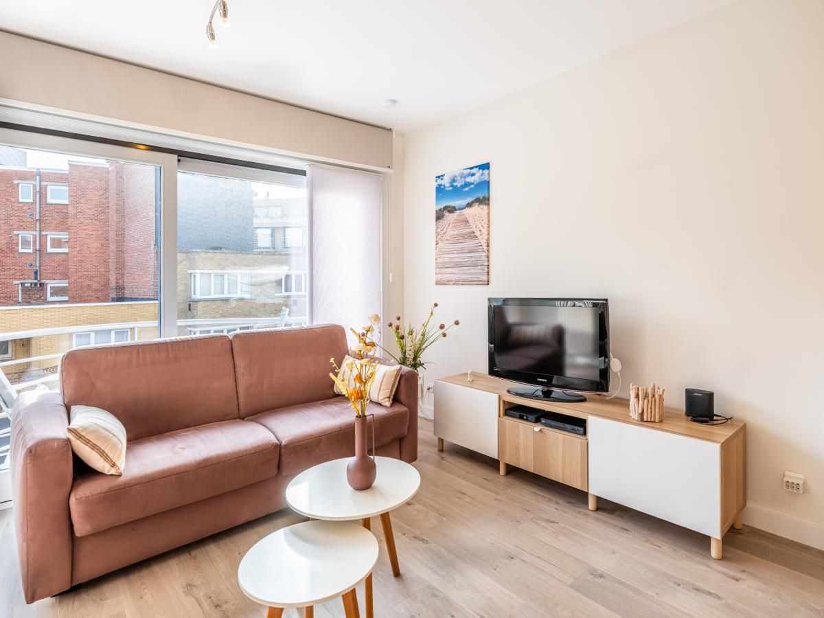 Gezellige woonkamer in Gaston Lejeune tweede vakantiehuis, Koksijde, West-Vlaanderen met comfortabele bank en modern interieur.