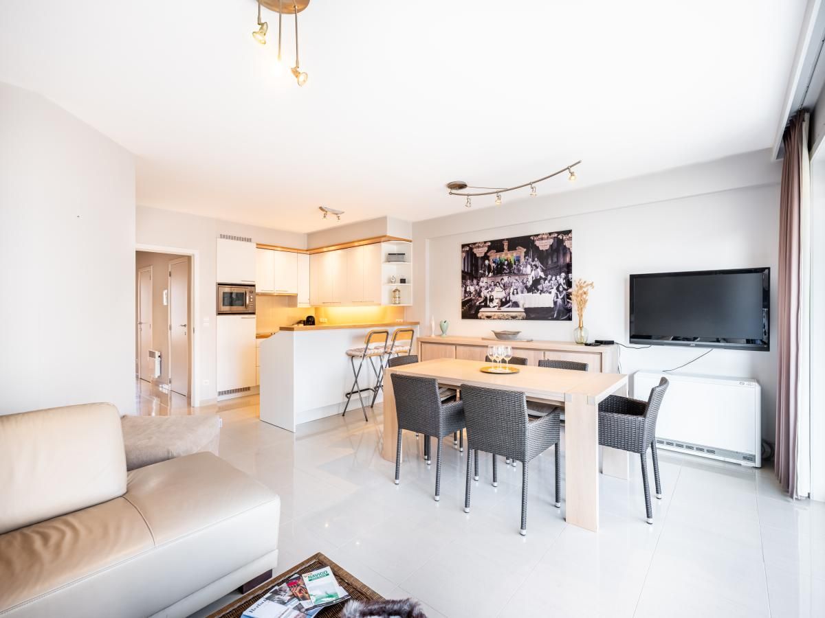 Modernes Wohnzimmer des Ferienhauses Guernsey second in Koksijde, Westflandern, Belgien mit offener Kueche und grosszuegigem Essbereich.