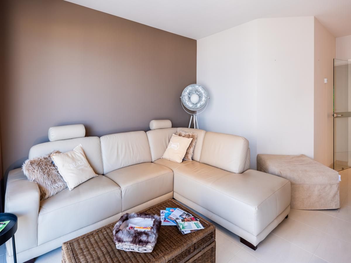 Stilvolles Wohnzimmer des Ferienhauses Guernsey second in Koksijde, Westflandern, mit bequemem Sofa und modernen Moebeln.