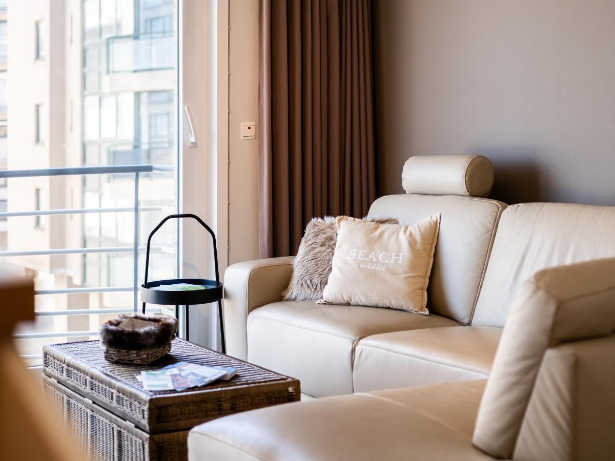 Gemuetliches Wohnzimmer des Ferienhauses Guernsey second in Koksijde, Westflandern, mit bequemem Sofa und Stadtblick.