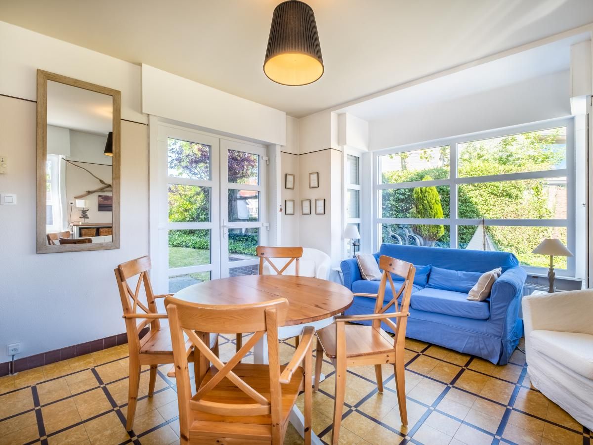 Gezellige woonkamer in Juvamy gelijkvloers vakantiehuis, Koksijde, met veel lichtinval en uitzicht op groene tuin, West-Vlaanderen, Belgie.
