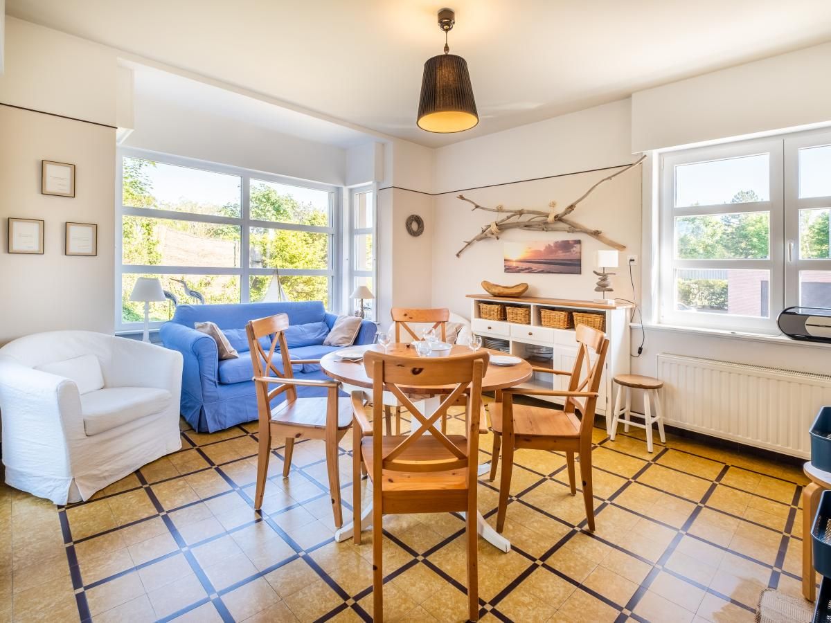 Gezellige eetkamer in Juvamy gelijkvloers, vakantiehuis in Koksijde, West-Vlaanderen, met veel licht en comfortabele zithoek.