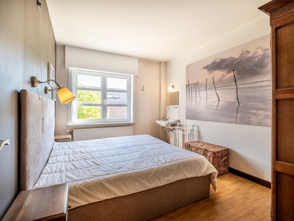 Sfeervolle slaapkamer in Juvamy gelijkvloers vakantiehuis, Koksijde, Belgie, met rustgevend interieur en grote ramen voor natuurlijk licht.