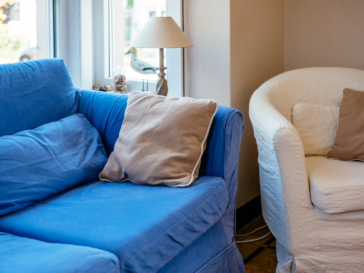 Gezellige zithoek in Juvamy gelijkvloers vakantiehuis, Koksijde, West-Vlaanderen, met comfortabele blauwe en witte fauteuils.