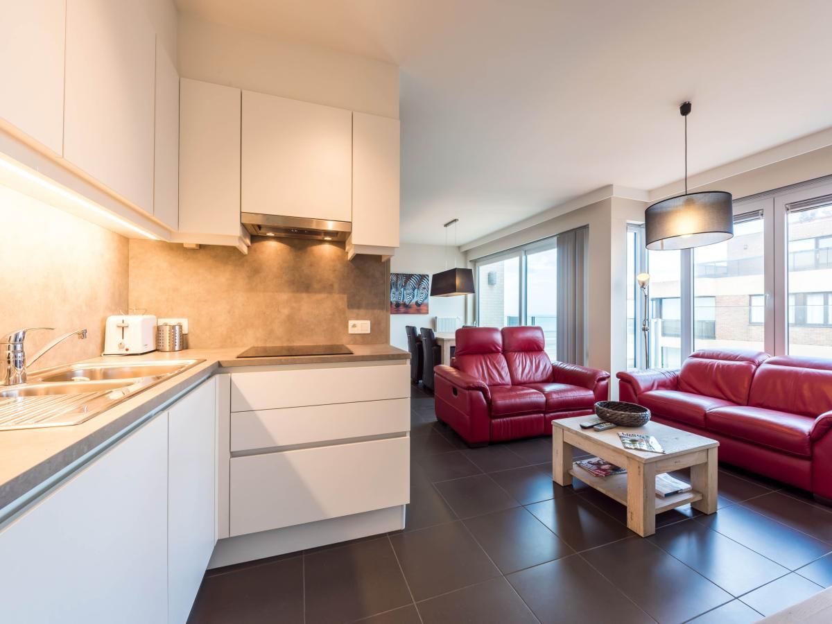 Moderne keuken en gezellige woonkamer in vakantiehuis De Dijk zesde, Koksijde, West-Vlaanderen, ideaal voor een ontspannen verblijf.