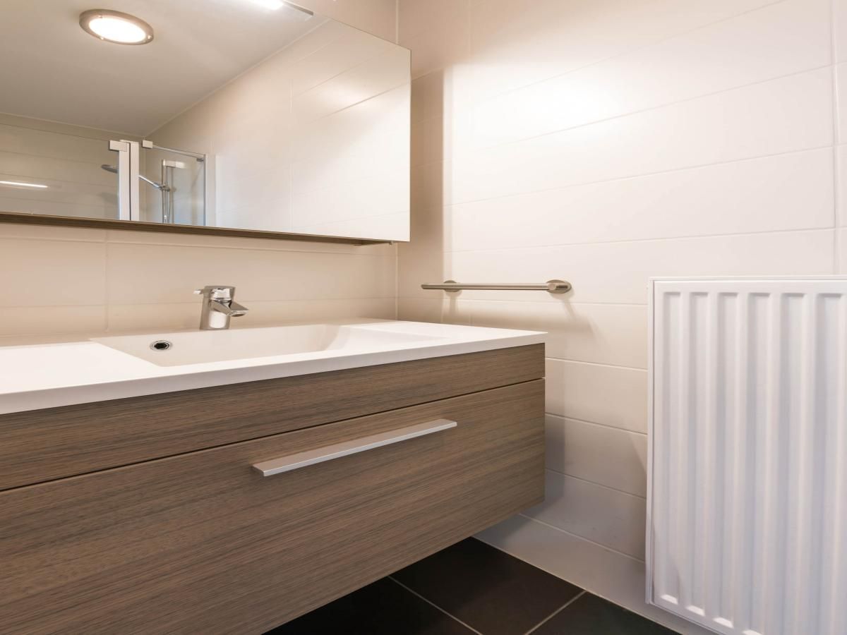 Moderne badkamer in De Dijk zesde vakantiehuis, Koksijde, West-Vlaanderen, Belgie met stijlvolle wastafel en spiegel.
