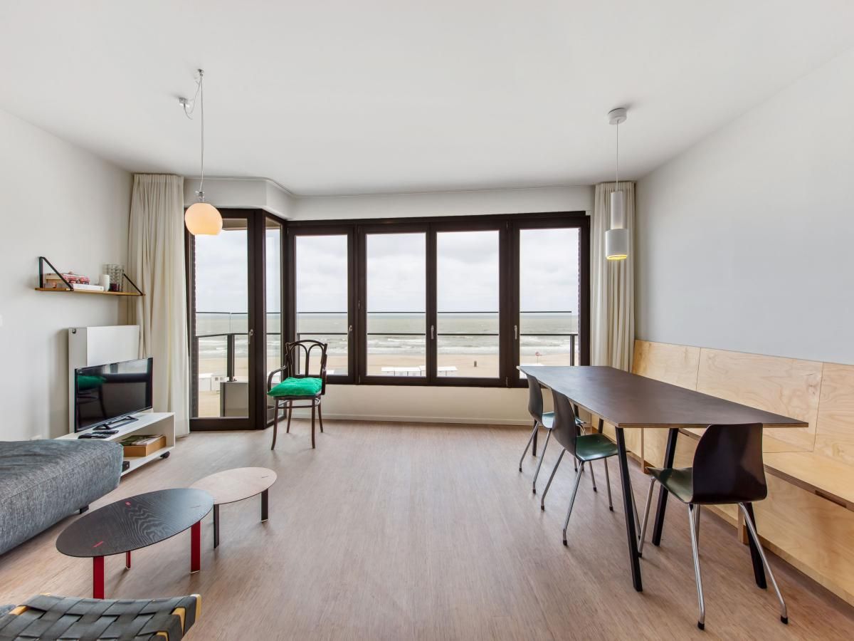 Ruime woonkamer van vakantiehuis De Meeuwen derde in Koksijde, Belgie, met panoramisch uitzicht op de kustlijn van West-Vlaanderen.