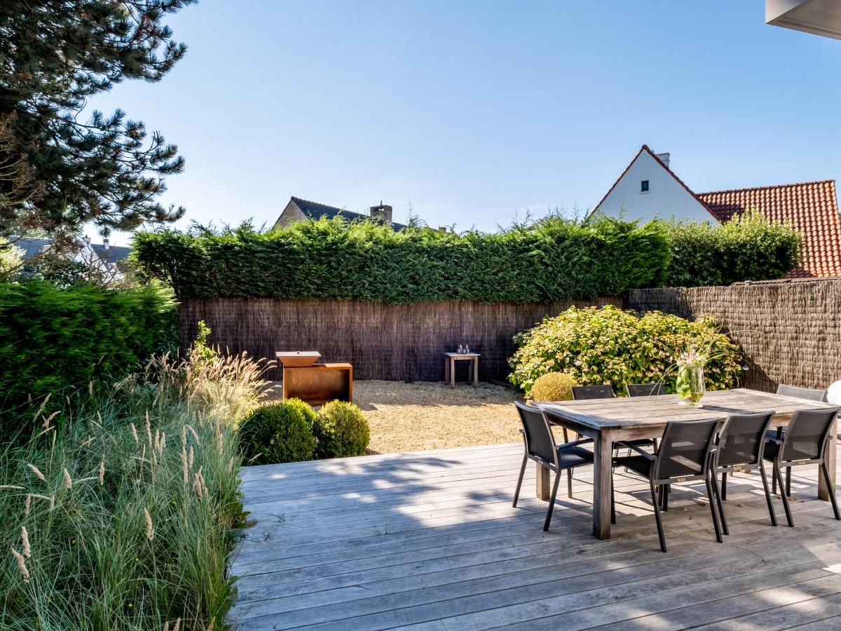 Geniet van de serene veranda bij vakantiehuis Tranquil in Koksijde, West-Vlaanderen, omgeven door groene natuur en rustgevende tuinen.