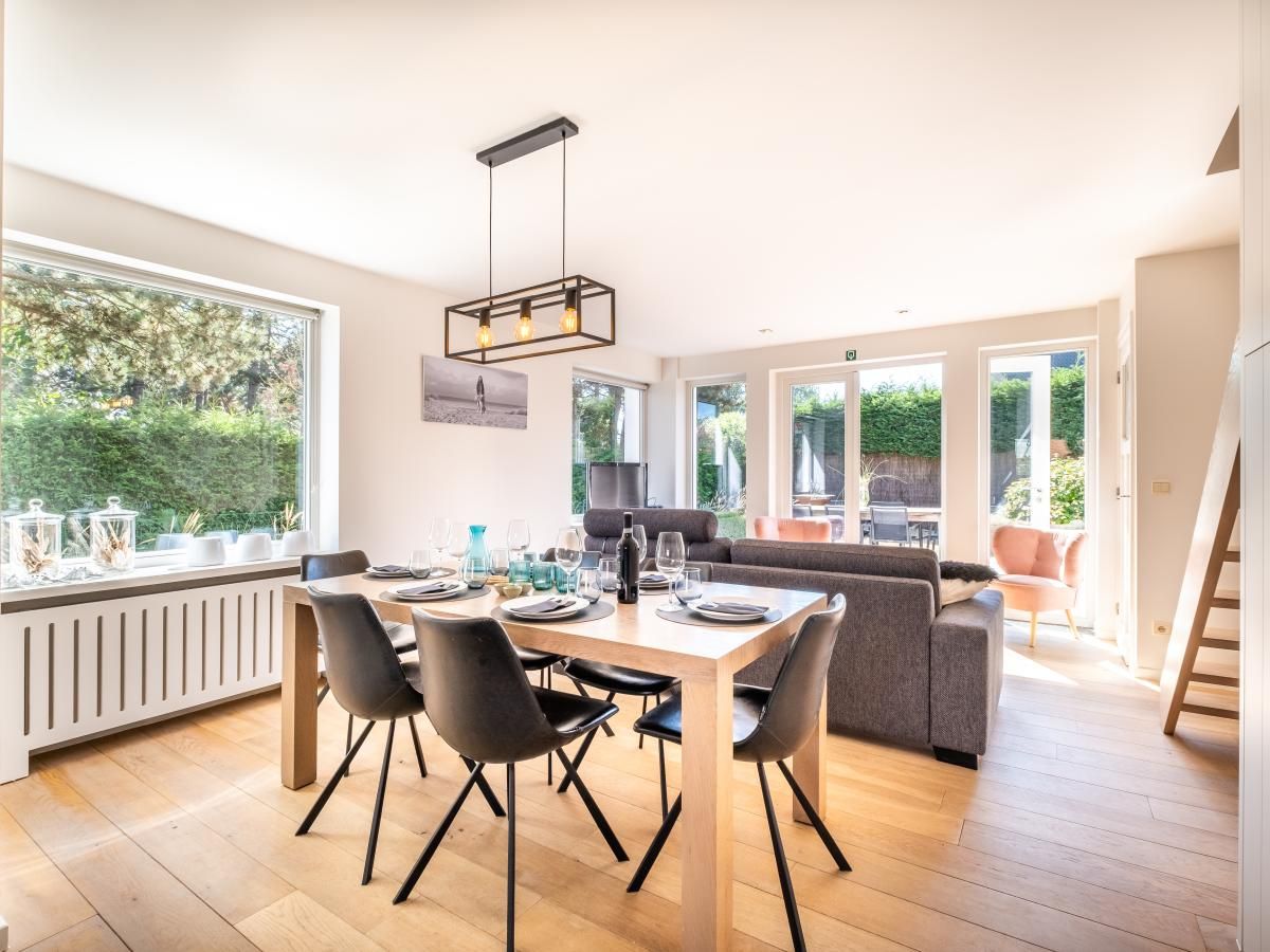 Gezellige eetkamer in Tranquil vakantiehuis, Koksijde, met uitzicht op de tuin, ideaal voor een ontspannen verblijf in West-Vlaanderen, Belgie.