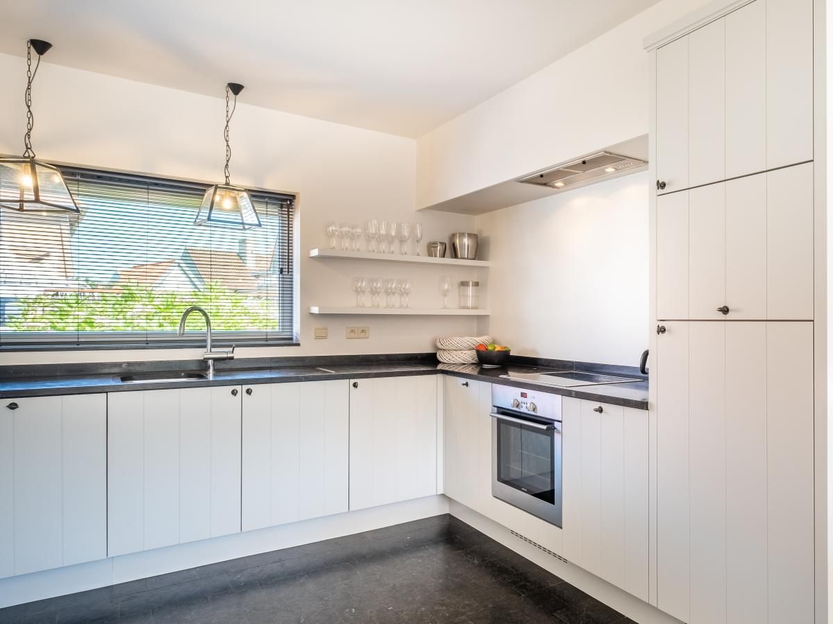 Moderne keuken in vakantiehuis Tranquil, Koksijde, West-Vlaanderen, met strakke inrichting en veel natuurlijk licht.