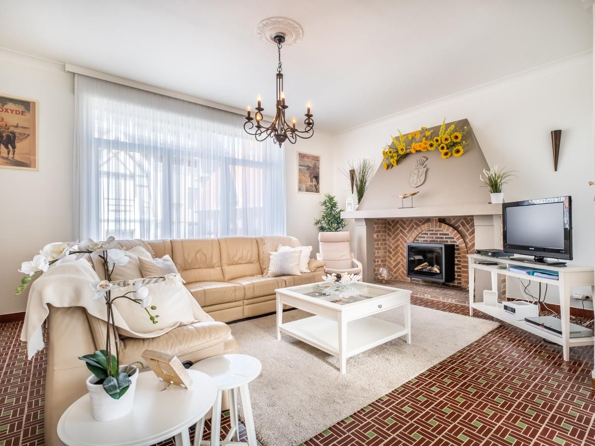 Gezellige woonkamer in vakantiehuis Porpoises, Koksijde, West-Vlaanderen, met comfortabele zithoek en sfeervolle open haard.