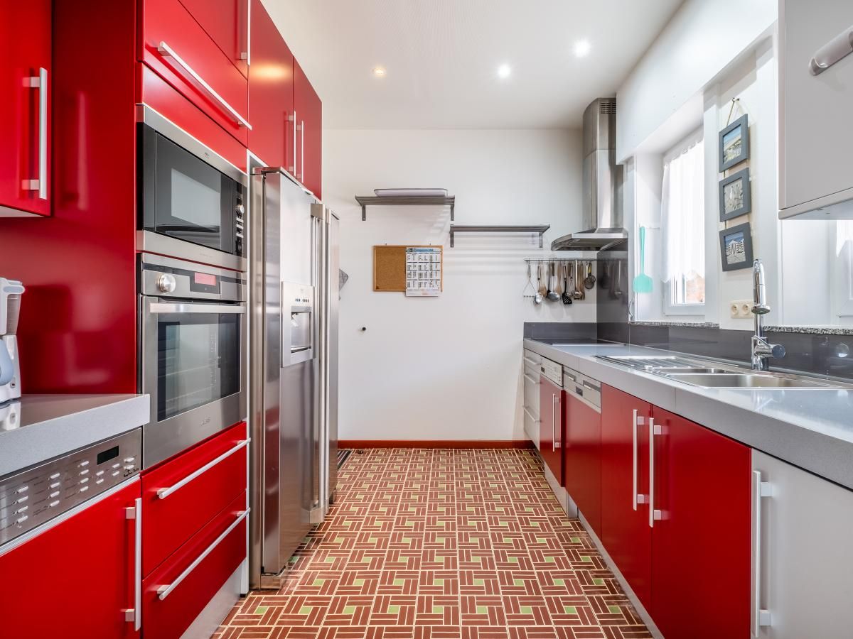 Moderne keuken in vakantiehuis Porpoises, Koksijde, Belgie met rode kasten en stijlvolle apparatuur voor een comfortabel verblijf.