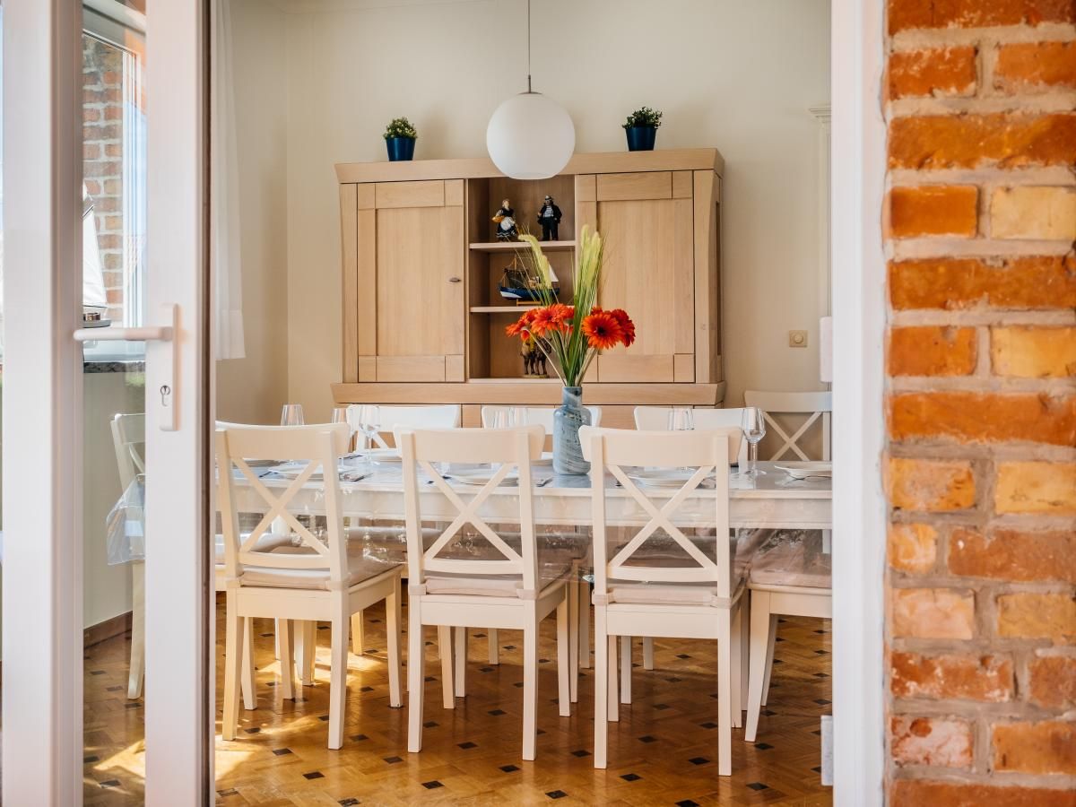 Gezellige eetkamer in vakantiehuis Porpoises, Koksijde, Belgie met houten meubels en zonnig uitzicht.