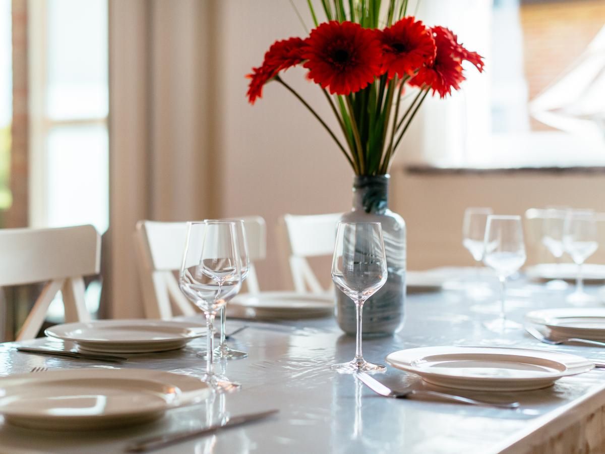 Stijlvolle eettafel in vakantiehuis Porpoises, Koksijde, West-Vlaanderen, met elegant servies en bloemen voor een gezellige maaltijd.