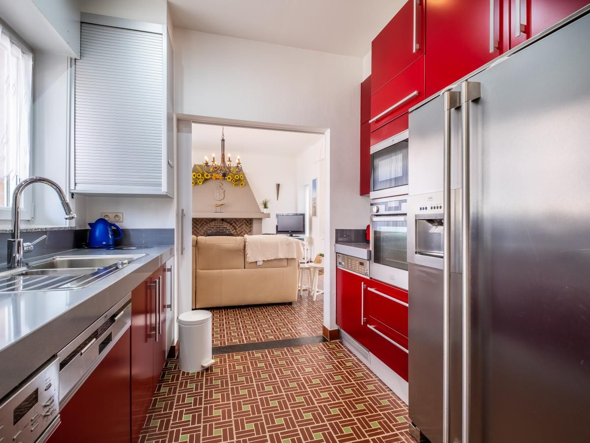 Moderne keuken in vakantiehuis Porpoises, Koksijde, West-Vlaanderen, met rode kasten en ruime opstelling voor een comfortabel verblijf.