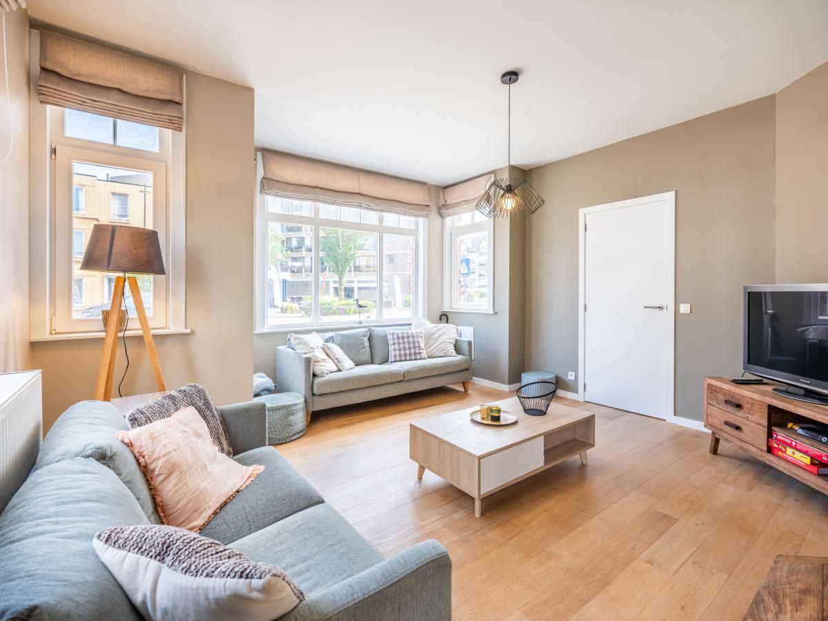 Cozy living room of vacation home Au Coin in Koksijde, West Flanders, with comfortable sitting area and lots of natural light.