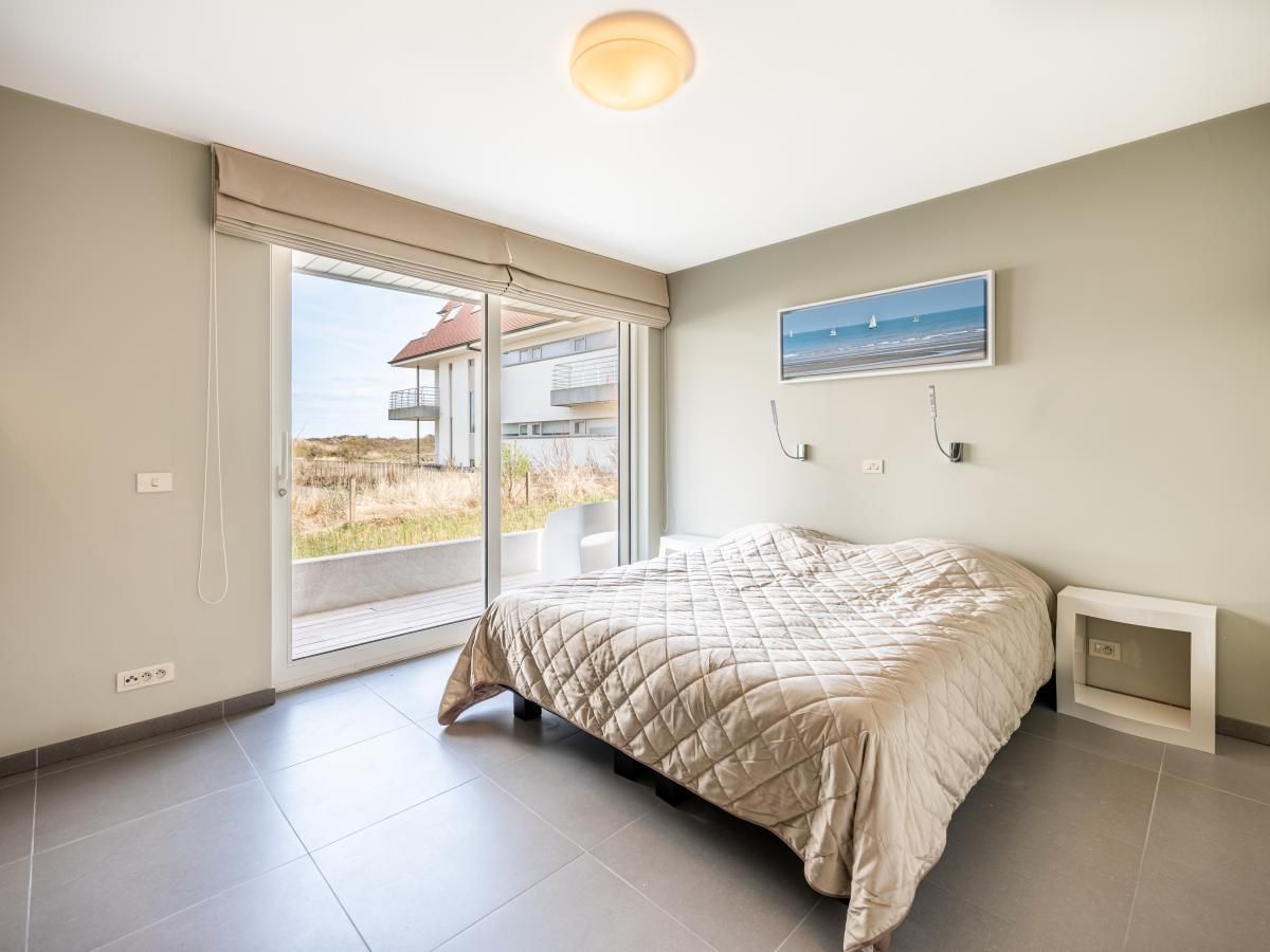 Lichte slaapkamer in Tinou Gelijkvloers vakantiehuis, Koksijde, West-Vlaanderen, met toegang tot terras en uitzicht op de natuur.