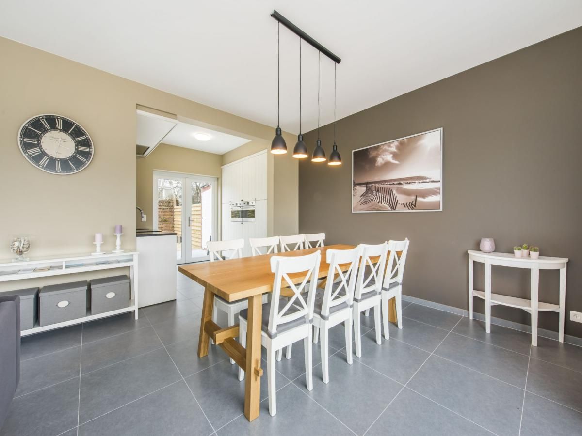 Cozy dining room in vacation home La Vachequirit, Koksijde, West Flanders, with modern decor and lots of natural light.