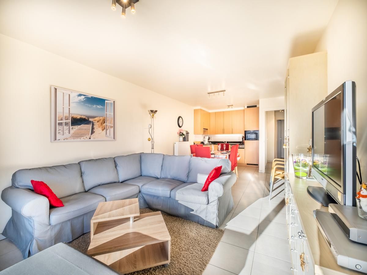Gezellige woonkamer van vakantiehuis Pablito trois in Koksijde, West-Vlaanderen, met comfortabele bank en moderne keuken.