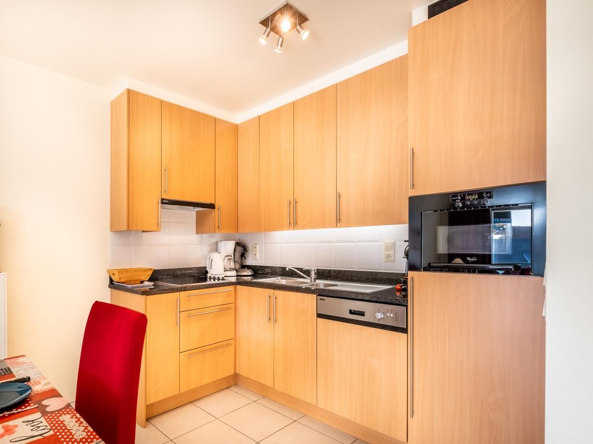 Moderne keuken in vakantiehuis Pablito trois in Koksijde, West-Vlaanderen, met houten kasten en moderne apparatuur voor een comfortabel verblijf.