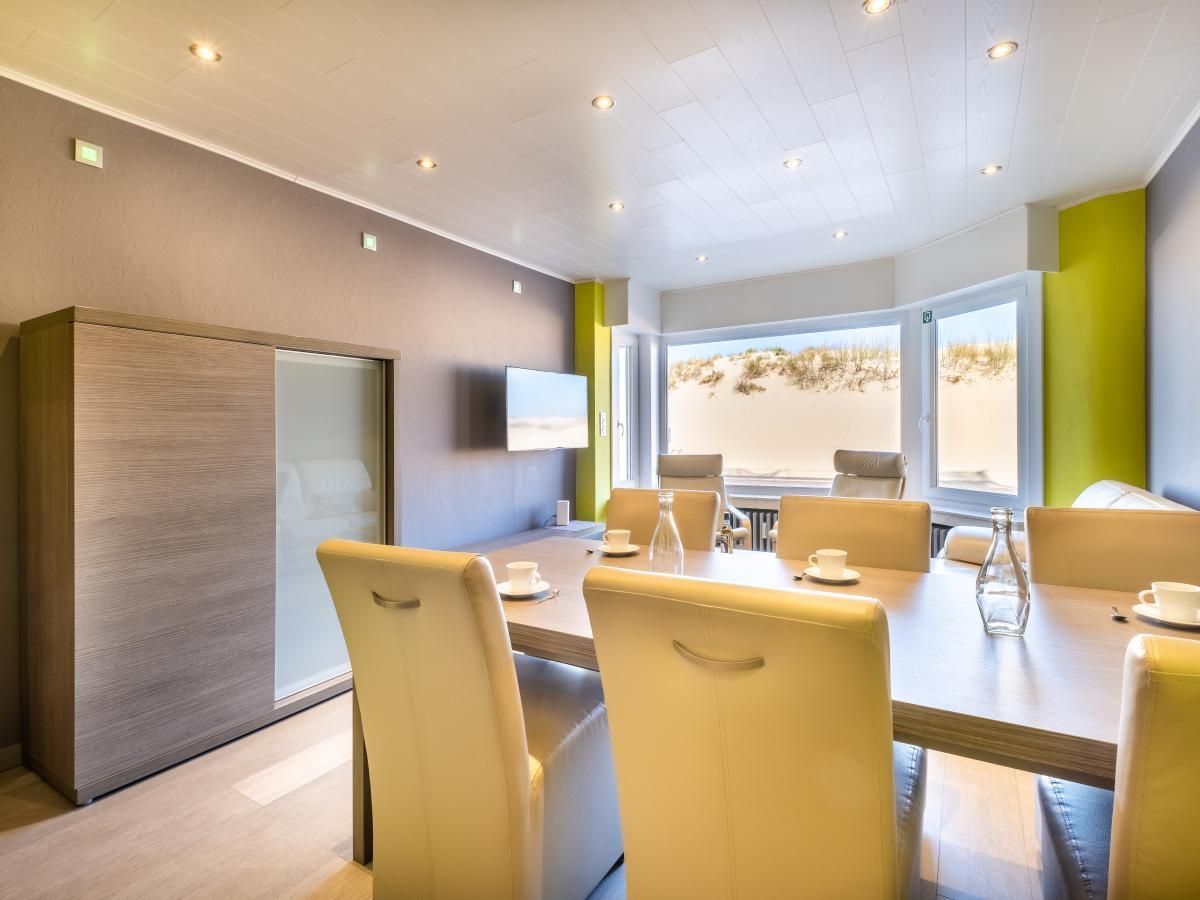 Moderne eetkamer van vakantiehuis Zeezicht GV in Koksijde, Belgie, met uitzicht op de duinen en een stijlvolle inrichting.