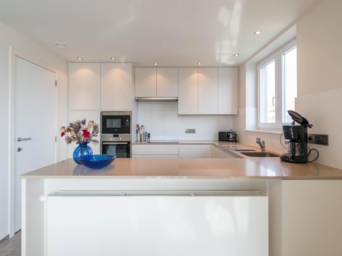 Moderne keuken in vakantiehuis Bon Accueil tweede in Koksijde, West-Vlaanderen, Belgie, met strakke witte kasten en veel natuurlijk licht.